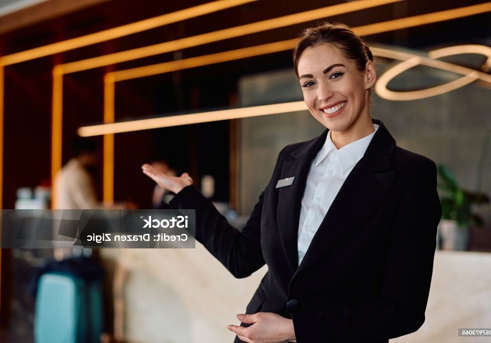 Happy concierge welcoming guests in a hotel and looking at camera.