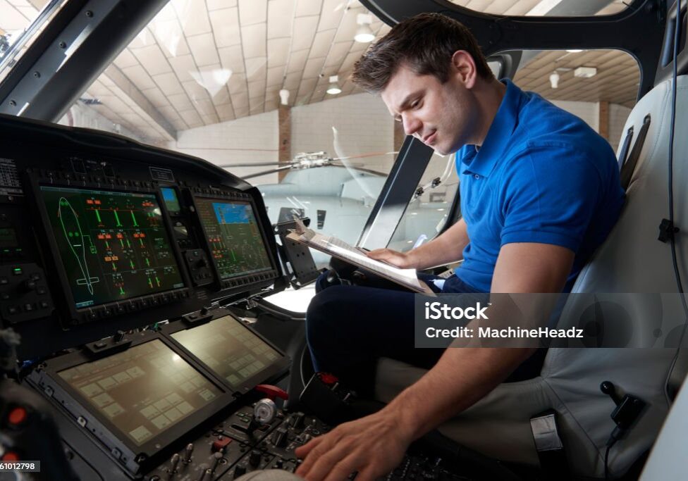 Male Aero Engineer With Clipboard Working In Helicopter Cockpit